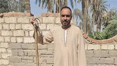 صورة لأحد الأهالي ممسكاً بثعبان بعد القضاء عليه 